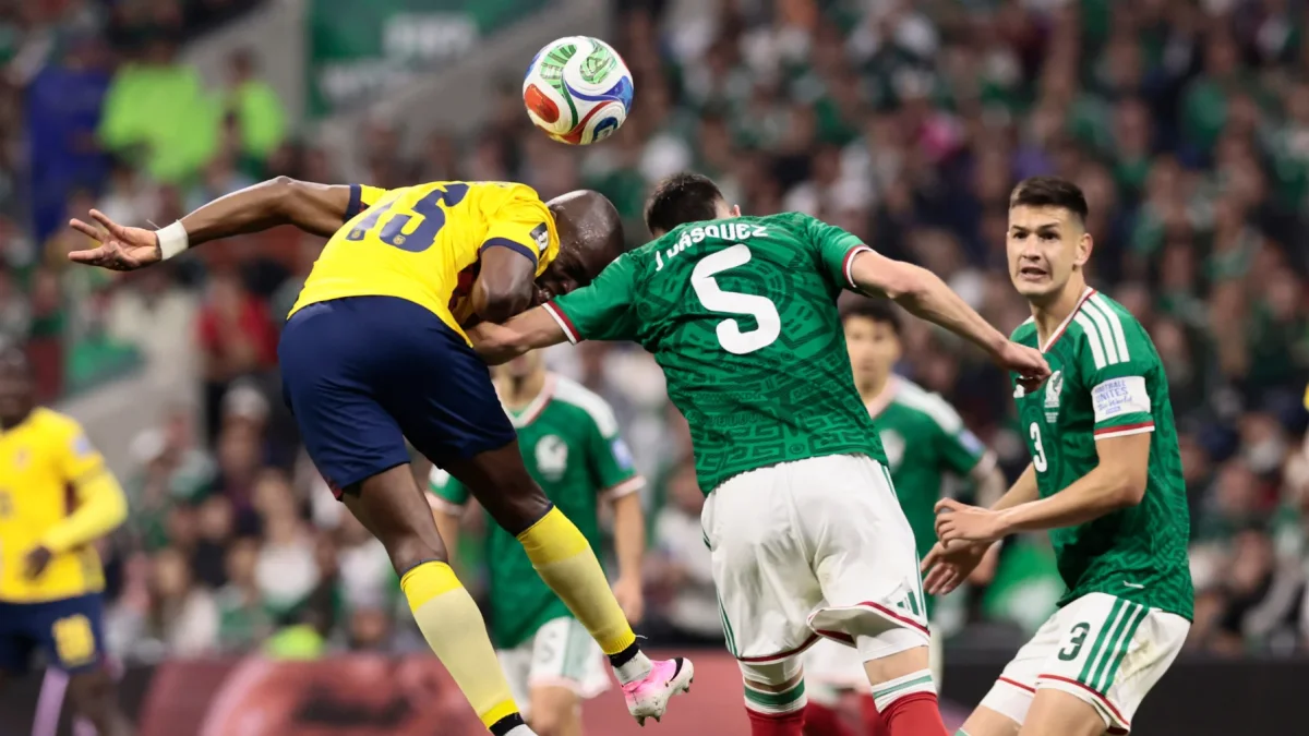 Johan Vásquez (c) de México disputa el balón con Enner Valencia de Ecuador.