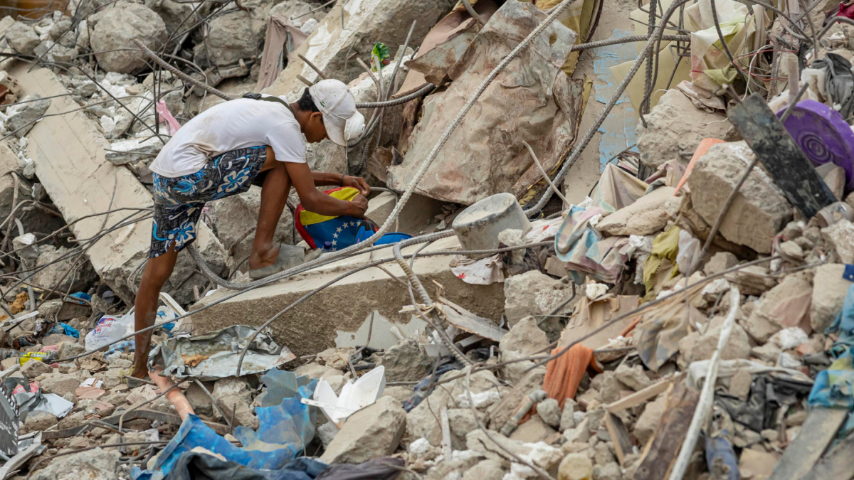 Una persona busca entre los escombros de edificios destruidos por terremotos en Caraballeda.