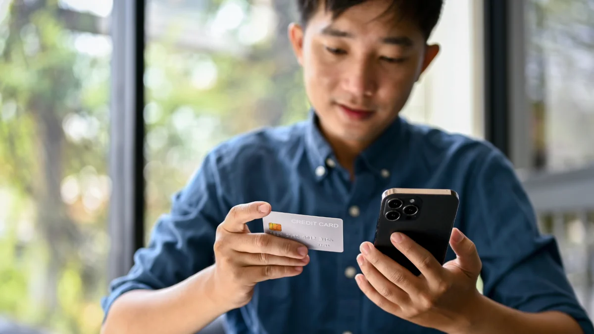 Uso de tarjeta y celular en una transacción digital, reflejo de operaciones que pueden generar errores de transferencia.