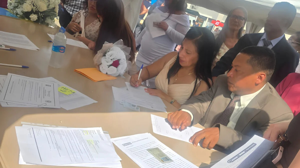 Una de las parejas firma el acta que oficializa su unión durante el matrimonio colectivo celebrado en Parque Samanes.