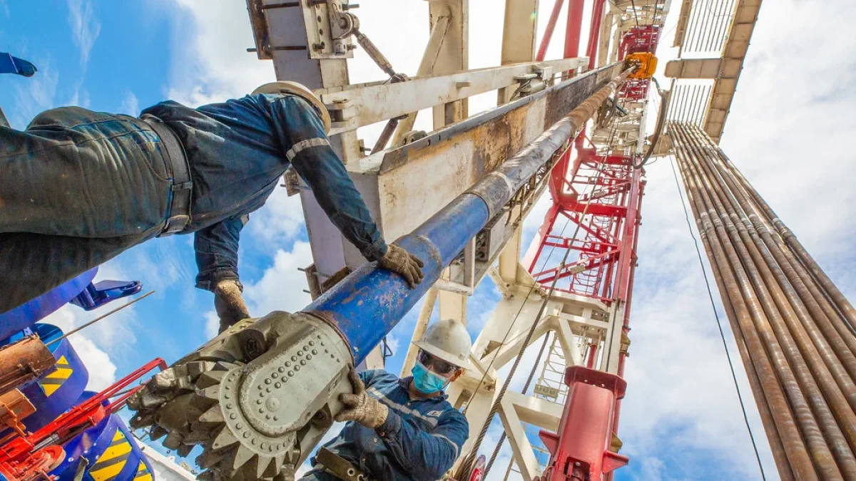 Dos personas hacen labor de mantenimiento en una torre donde se extrae petróleo.