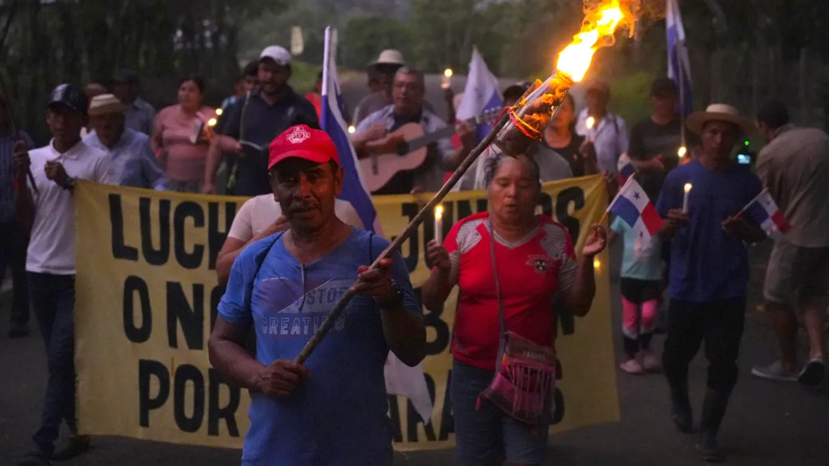 Campesinos sostienen banderas y velas en una vigilia en rechazo al decreto ejecutivo que ordena la clausura de los cementerios comunitarios.