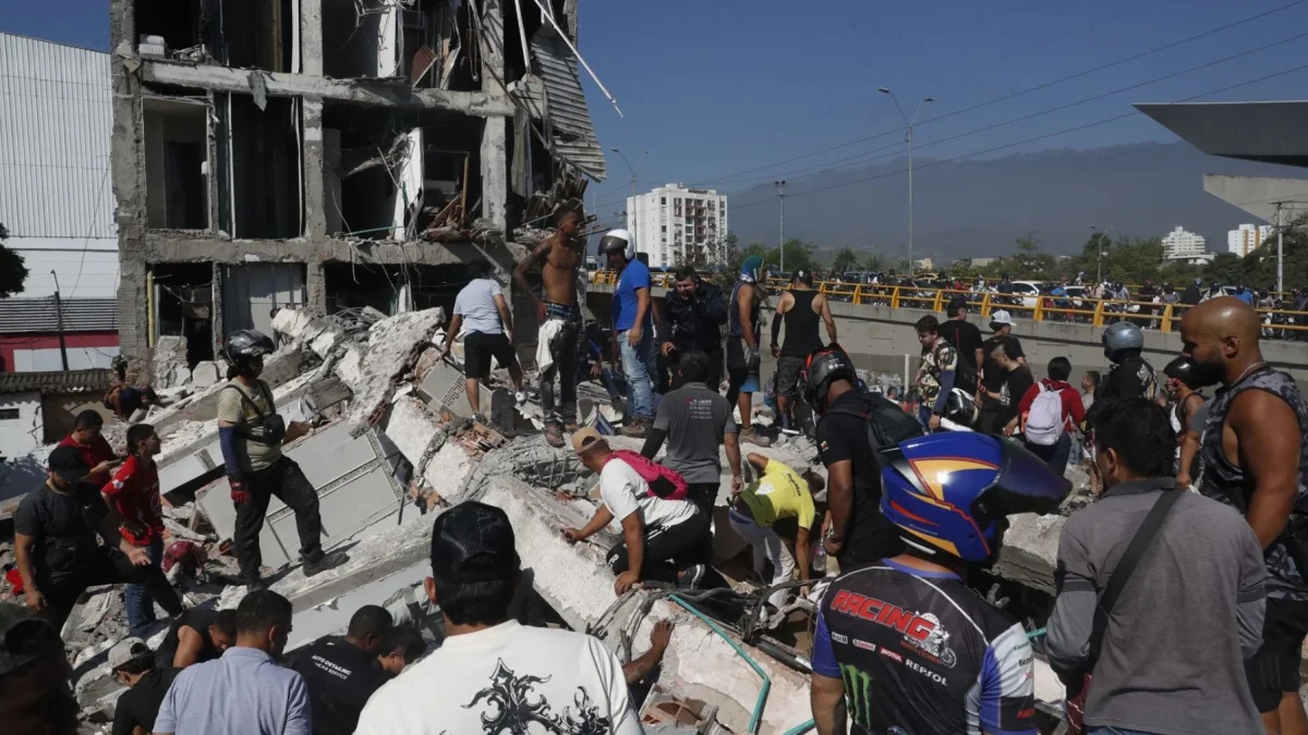 Personas caminan sobre los escombros de un edificio colapsado este lunes, en Cali (Colombia)