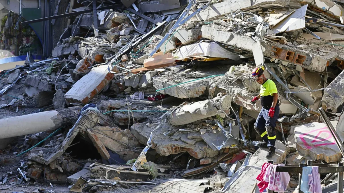 Un integrante de organismos de socorro camina sobre los escombros de una edificación destruida tras el terremoto de magnitud 7,4 que sacudió la víspera la mayor parte de Colombia, este martes en Pereira (Colombia).