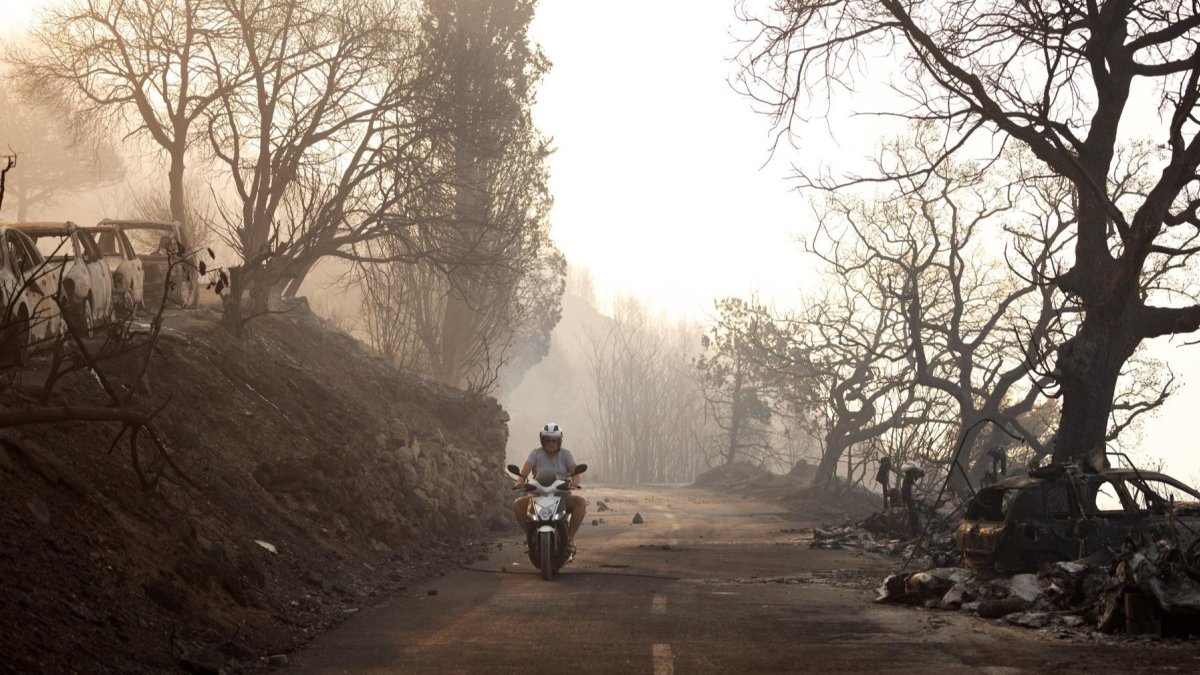 Un hombre pasa cerca de coches quemados tras un incendio forestal cerca de la ciudad de Omis, Croacia, el 14 de agosto de 2026.
