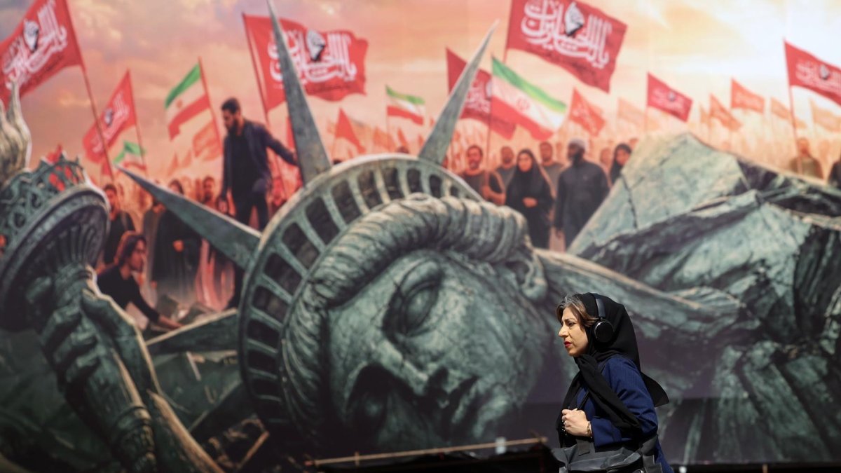 Una mujer iraní camina junto a un cartel antiestadounidense en la plaza Enghelab en el centro de Teherán, Irán, el 13 de agosto de 2026.