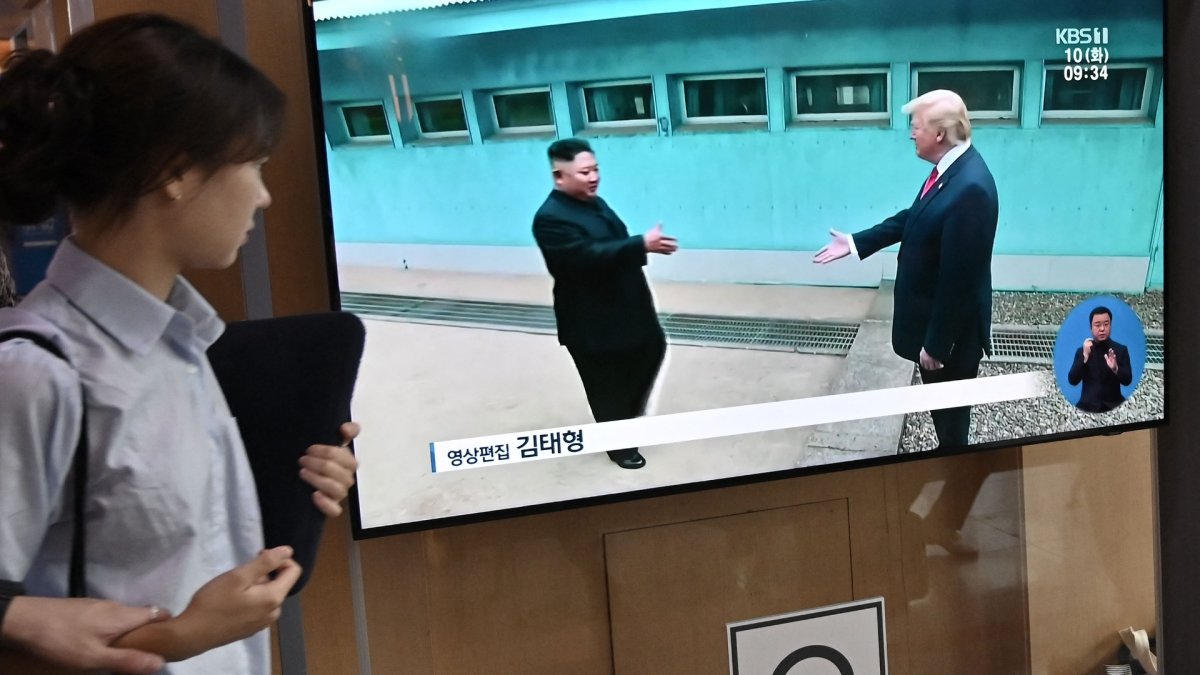 Una mujer pasa junto a una pantalla de televisión que muestra reunión entre el presidente Donald Trump y el líder norcoreano Kim Jong Un, en estación de tren de Seúl.