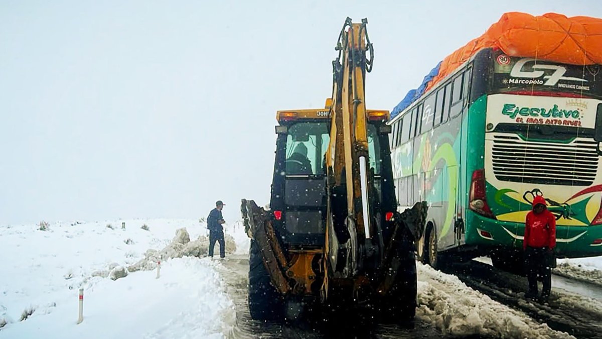 Operarios trabajando con maquinaria amarilla para limpiar una carretera durante una nevada en La Paz (Bolivia).