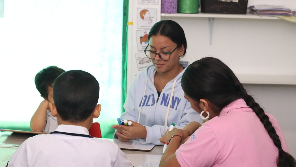 Una maestra junto a jóvenes en un centro de apoyo terapéutico.