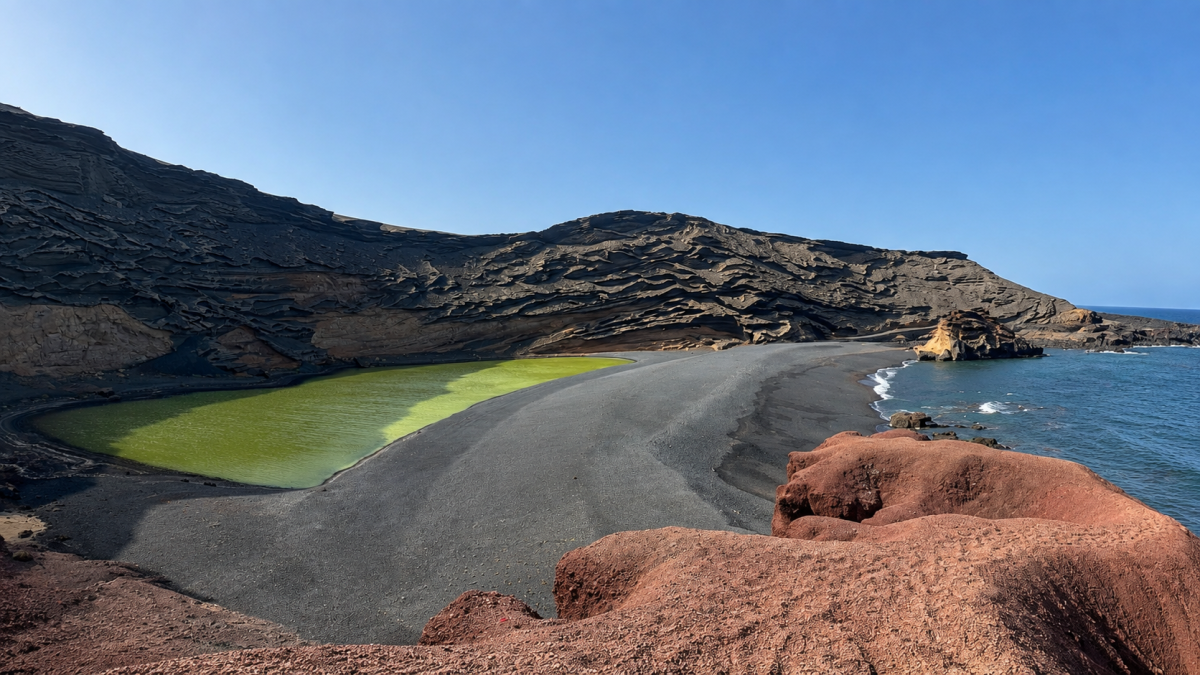 El Charco de los Clicos sorprende por sus aguas verdes rodeadas de arena negra, rocas rojizas y el azul del océano.