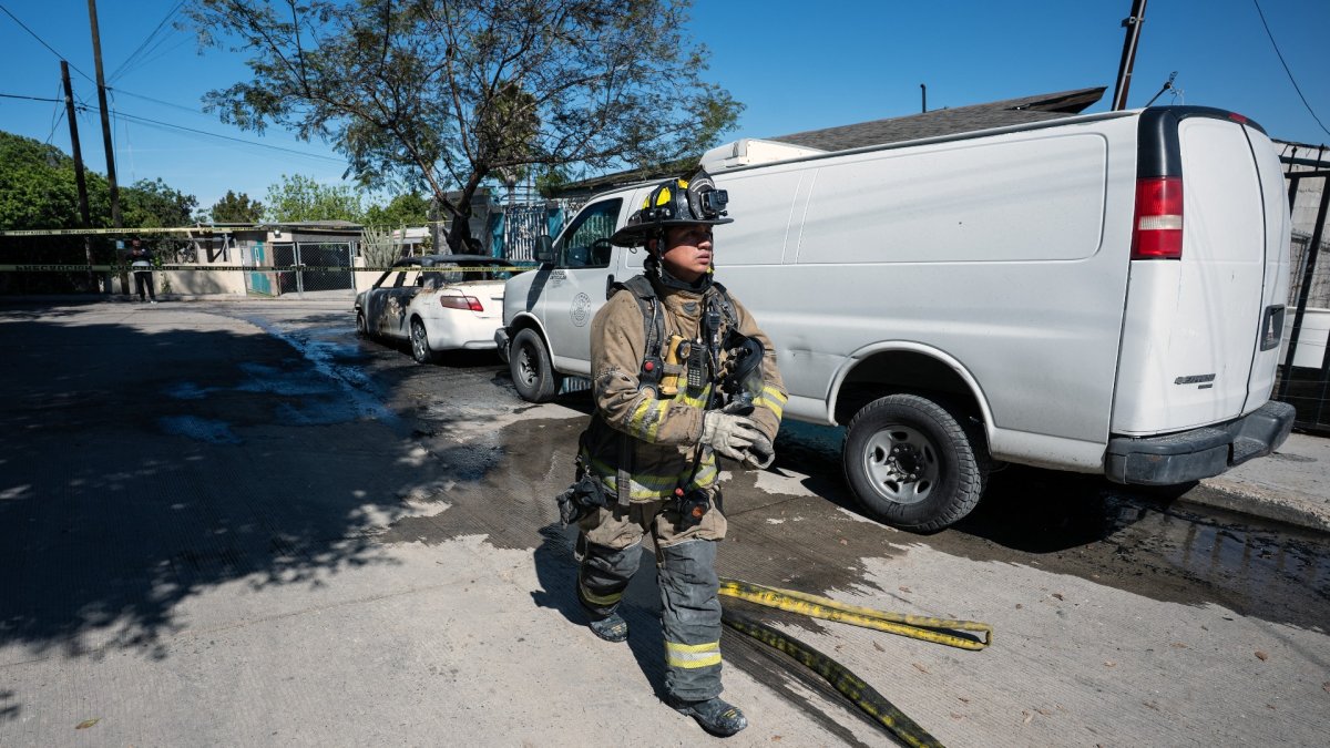 Un bombero pasa junto a un auto quemado, incendiado por grupos del crimen organizado, en respuesta a una operación contra el Cártel Jalisco Nueva Generación, en Tijuana.
