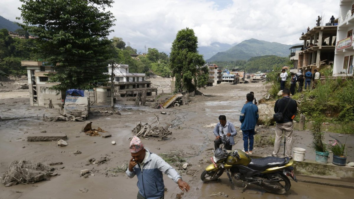 Campesinos avanzan entre el lodo en Trishuli, en el distrito nepalí de Nuwakot, tras una riada repentina.