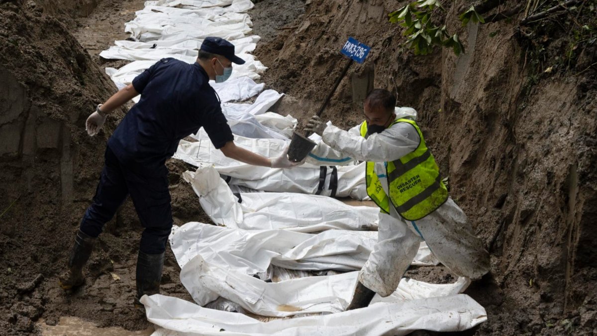 Agentes de la policía nepalí realizan un entierro masivo de víctimas de las inundaciones que golpearon el norte de Nepal.
