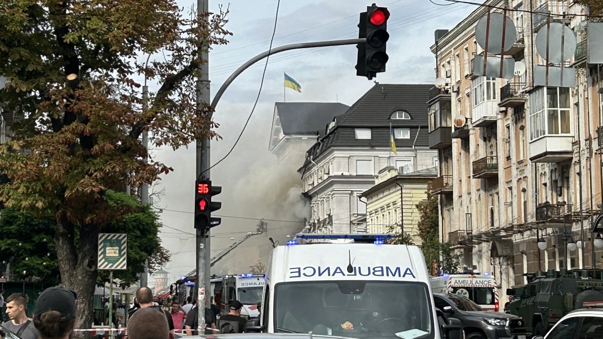 Personas observan cómo rescatistas trabajan para extinguir un incendio tras un ataque aéreo en Kiev.