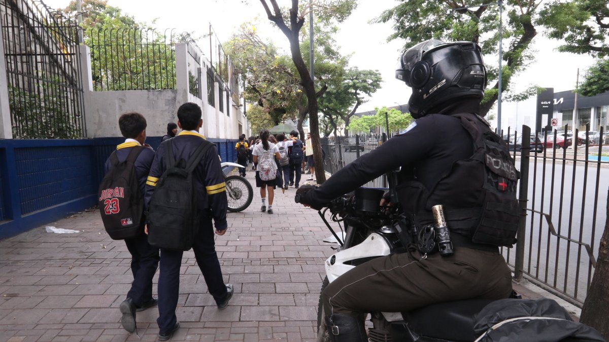 Agente policial custodia el ingreso de estudiantes a un colegio en el norte de Guayaquil.