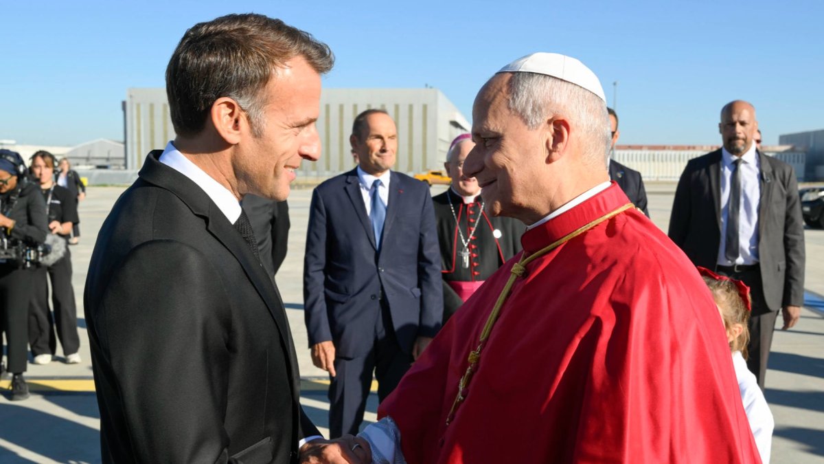 El papa León XIV (d) es recibido por el presidente francés, Emmanuel Macron (i) a su llegada al aeropuerto de París-Orly, Francia.