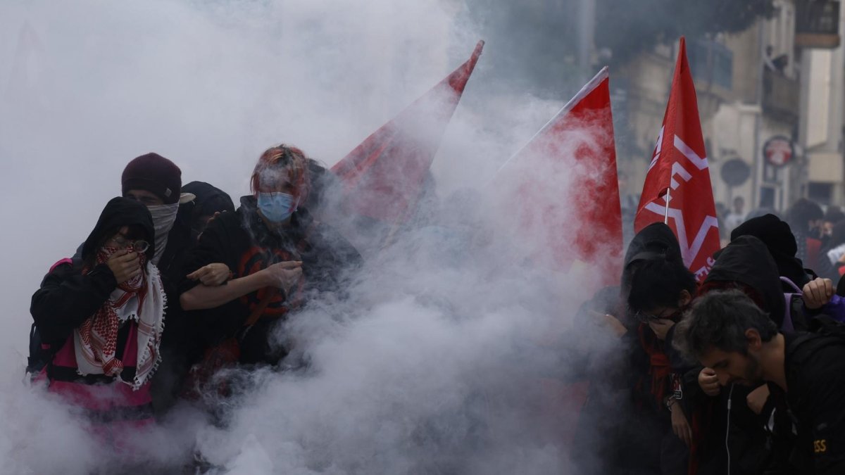 Estudiantes de secundaria permanecen en medio de gases lacrimógenos mientras estallan enfrentamientos entre estudiantes y la policía antidisturbios.