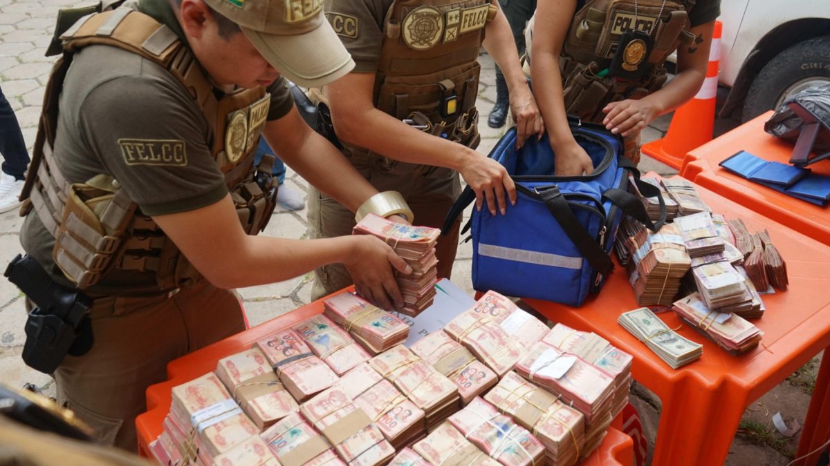 Integrantes de la Fuerza Especial de Lucha Contra el Crimen (FELCC) de Bolivia cuentan billetes que fueron encontrados en una ambulancia.