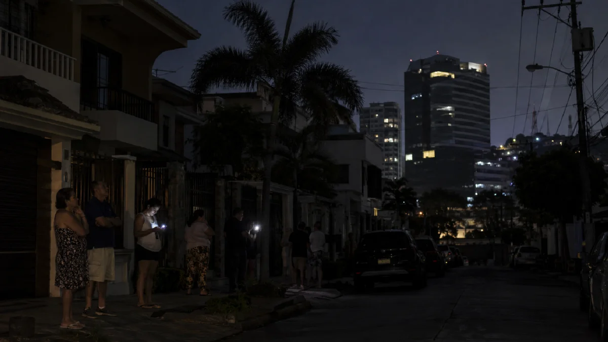 Vecinos permanecen en una calle oscura durante un corte de luz en Guayaquil.