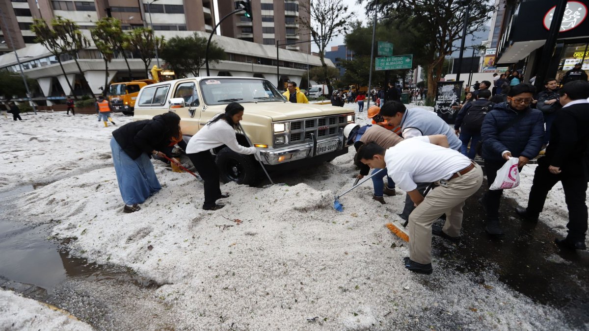 Ciudadanos colaboraron en el retiro del hielo acumulado sobre los vehículos que quedaron cubiertos por la fuerte granizada en Quito.