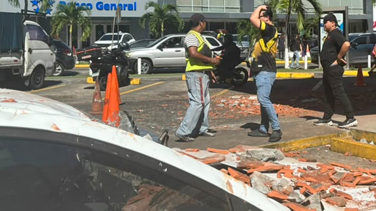 Personas observan un vehículo afectado por los restos de un edificio en Ciudad de Panamá, tras un terremoto de magnitud 7,7 que sacudió el país este viernes 9 de octubre.