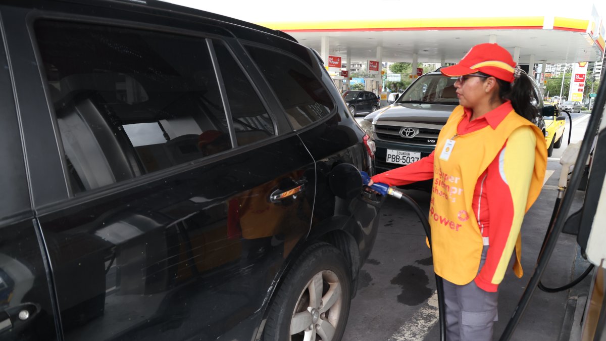 Una trabajadora de una gasolinera despacha el combustible para un carro.