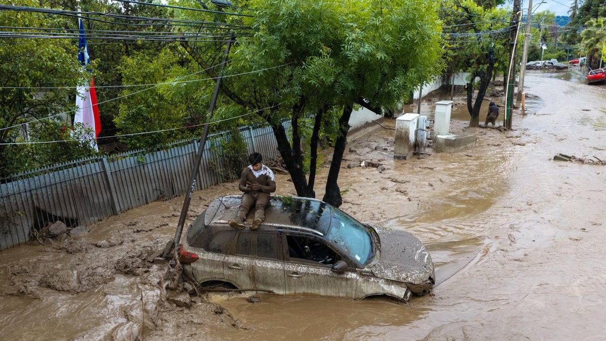 Una persona se refugia sobre un vehículo afectado por un aluvión, el jueves 8 de octubre de 2026, en la comuna de Las Condes, en Santiago de Chile.
