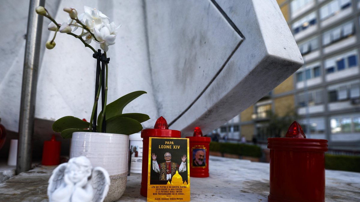 Una fotografía del papa León XIV colocada bajo la estatua de Juan Pablo II frente al Hospital Universitario Agostino Gemelli, donde el pontífice se encuentra hospitalizado, en Roma.
