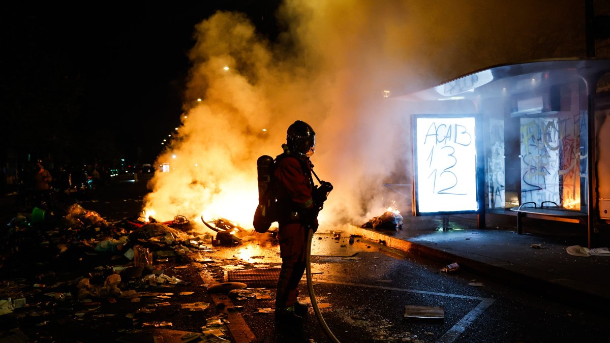 Un bombero francés interviene ante barricadas en llamas en una calle.