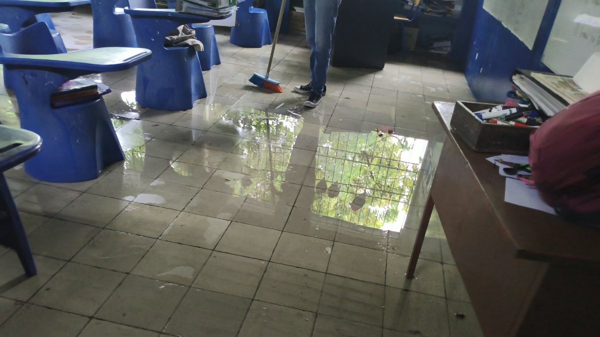 Un trabajador de una escuela en Guayaquil intenta retirar el agua acumulada en un aula.
