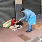 Un voluntario entrega comida a una persona que duerme en la calle.