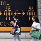 Masked pedestrians walk past a billboard reminding people on social distancing practices amid the COVID-19 coronavirus pandemic in Tokyo on June 23, 2020. (Photo by CHARLY TRIBALLEAU / AFP)