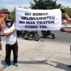 Dos motociclistas sostienen un cartel en el que piden no ser tratados como delincuentes.
