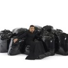 Arquitecto, artista y diseñador Harry Nuriev en medio de su obra "The Trash Bag Sofa" -El sofá de bolsas de basura- (2022).