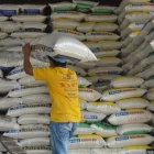 Una persona carga un saco de arroz en una bodega.