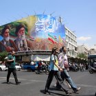 Iraníes pasan frente a una gran valla publicitaria con los difuntos líderes supremos iraníes, los ayatolás Ruhollah Jomeini y Ali Jameneí, en una calle de Teherán, Irán.