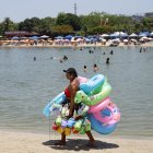 AME640. RÍO DE JANEIRO (BRASIL), 26/12/2025.- Una mujer vende flotadores y juguetes para la arena en la playa del lago artificial 'Piscinão de Ramos' este viernes, en Río de Janeiro (Brasil). El Instituto Nacional de Meteorología de Brasil (Inmet) emitió este viernes una alerta roja para todo el territorio de los estados de São Paulo y Río de Janeiro por una ola de calor que, previsiblemente, se prolongará hasta el lunes. EFE/ Antonio Lacerda
