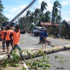 Trabajadores retiran un árbol caído y un pilón eléctrico (L) destruido a la altura del tifón Phanfone en la ciudad de Salcedo, provincia de Samar Oriental, este 26 de diciembre.