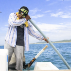 Práctica. En su labor diaria, el pescador escucha el sonido de los peces a través de un tubo plástico.