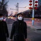 PEKÍN. Una pareja de pequineses caminan por un sector de calles desoladas. Así son los días en la capital china.
