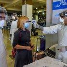 Personal de servicios de salud que usa equipo de protección verifica la temperatura corporal de un pasajero, en Kabul, por disposición de las autoridades afganas.