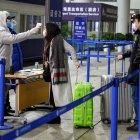 Personal de seguridad verifica la temperatura de los pasajeros que llegan al Aeropuerto Internacional de Shanghai.