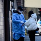A security guard wearing a protective facemask checks the temperature of a woman before she enters a hospital in Shanghai on February 18, 2020.   The World Health Organization has warned against a global over-reaction to the new coronavirus epidemic following panic-buying, event cancellations and concerns about cruise ship travel, as China"s official death toll neared 1,900 on February 18.
 / AFP / NOEL CELIS

 CHINA-HEALTH-VIRUS