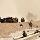 KANDAHAR. Soldados estadounidenses vigilan cerca de los restos de su vehículo en el sitio de un ataque suicida talibán.