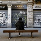 Una persona sentada frente a los locales comerciales cerrados de la vía Paolo Sarpi, conocida como el "ChinaTown" de Milán.
