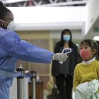 NAIROBI. Un trabajador de la salud de Kenia examina a una niña que arriba en un vuelo desde china en el Aeropuerto Internacional "Jomo Kenyatta".
