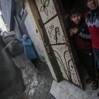 Niños palestinos observan desde la puerta de su casa como un hombre desinfecta una calle cercana este martes en Gaza, Palestina. Tanto la Autoridad Nacional Palestina, que gobierna Cisjordania ocupada, como Hamás, que controla de facto la Franja de Gaza, también han reaccionado con severidad al coronavirus, y hasta ahora se registran muy pocos casos. EFE/Mohammed Saber -FOTODELDÍA- PALESTINA CORONAVIRUS PANDEMIA COVID19