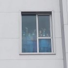 Los galenos a través de una ventana de la casa de salud, cubiertos de mascarillas y la protección requerida para su área, levantaron las manos en señal de victoria.