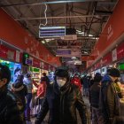 Las personas que usan máscaras protectoras visitan un mercado en Beijing, China