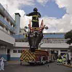 Fireman Henry Garcia stands on the top of a fire engine"s ladder from where he plays the trumpet to lift the spirits of personnel of the health sector and patients during the novel coronavirus COVID-19 pandemic, at the emergency door of the Carlos Andrade Marin Hospital in Quito, on April 18, 2020. (Photo by Rodrigo BUENDIA / AFP)